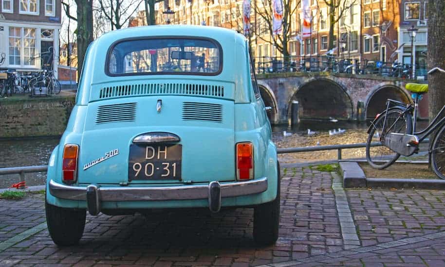 Ein parkender hellblauer Fiat 500 im Amsterdamer Grachtengürtel