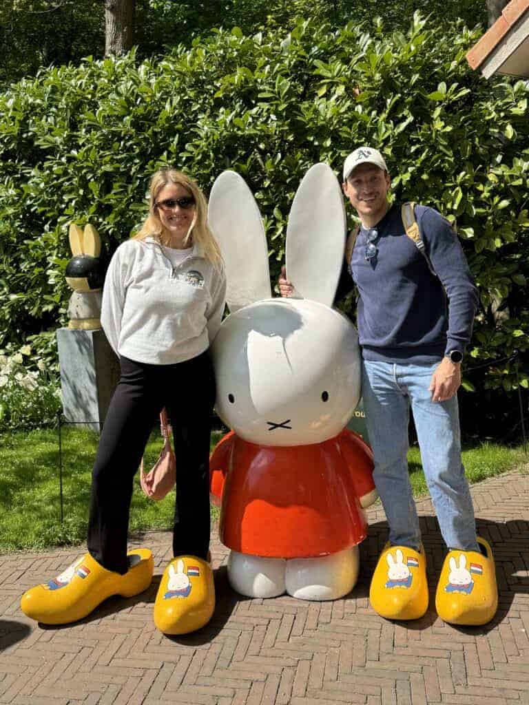 Two people standing next to a large white rabbit statue. They are wearing yellow shoes.