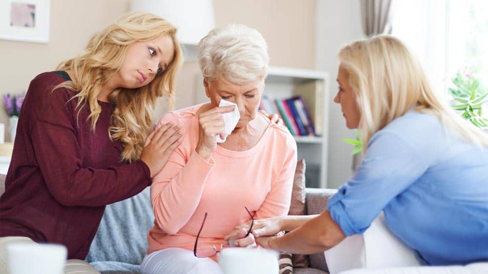 mother and daughter consoling a woman who is crying