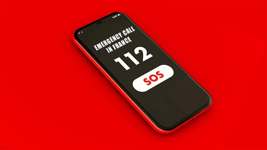 cell phone on red background with EU emergency number displayed which can be used in France and all of the EU