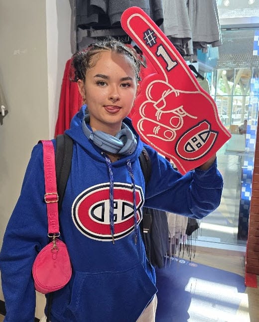 Catherine in a Montreal Canadiens hoodie holding a foam finger — a kid raised in France, fully at home in Quebec