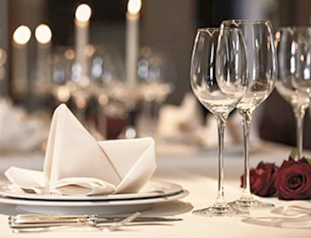 A table setting with wine glasses, napkins and candles.