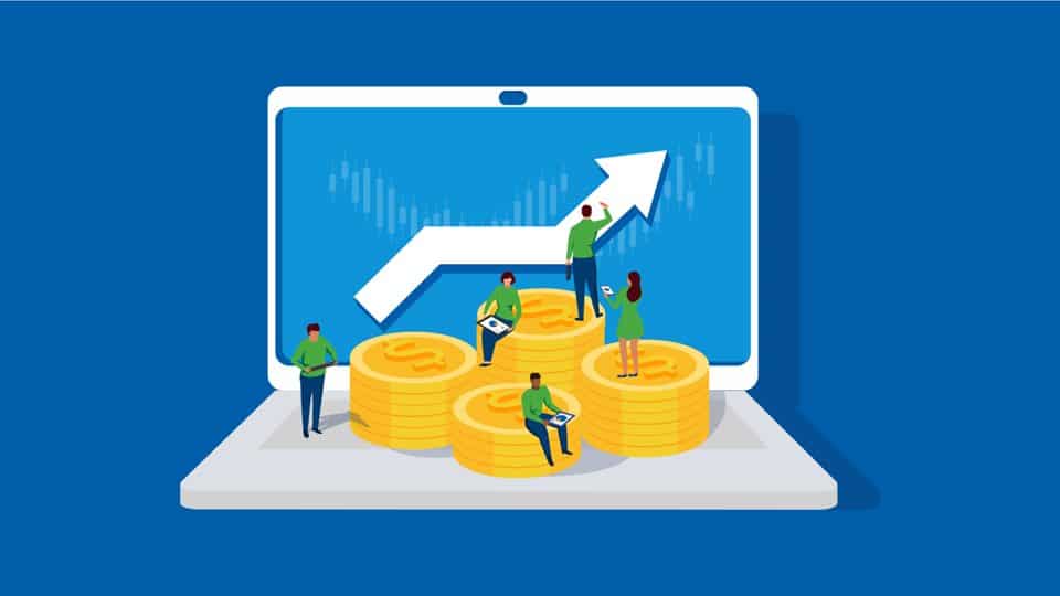 A group of people standing on a laptop with stacks of coins on it.