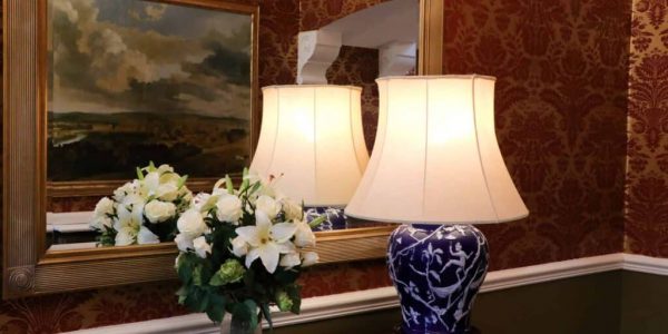 A hallway with a lamp and a mirror.