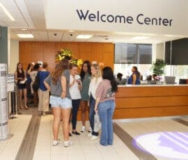 Group of young women in Houff Center lobby under the Welcome Center sign