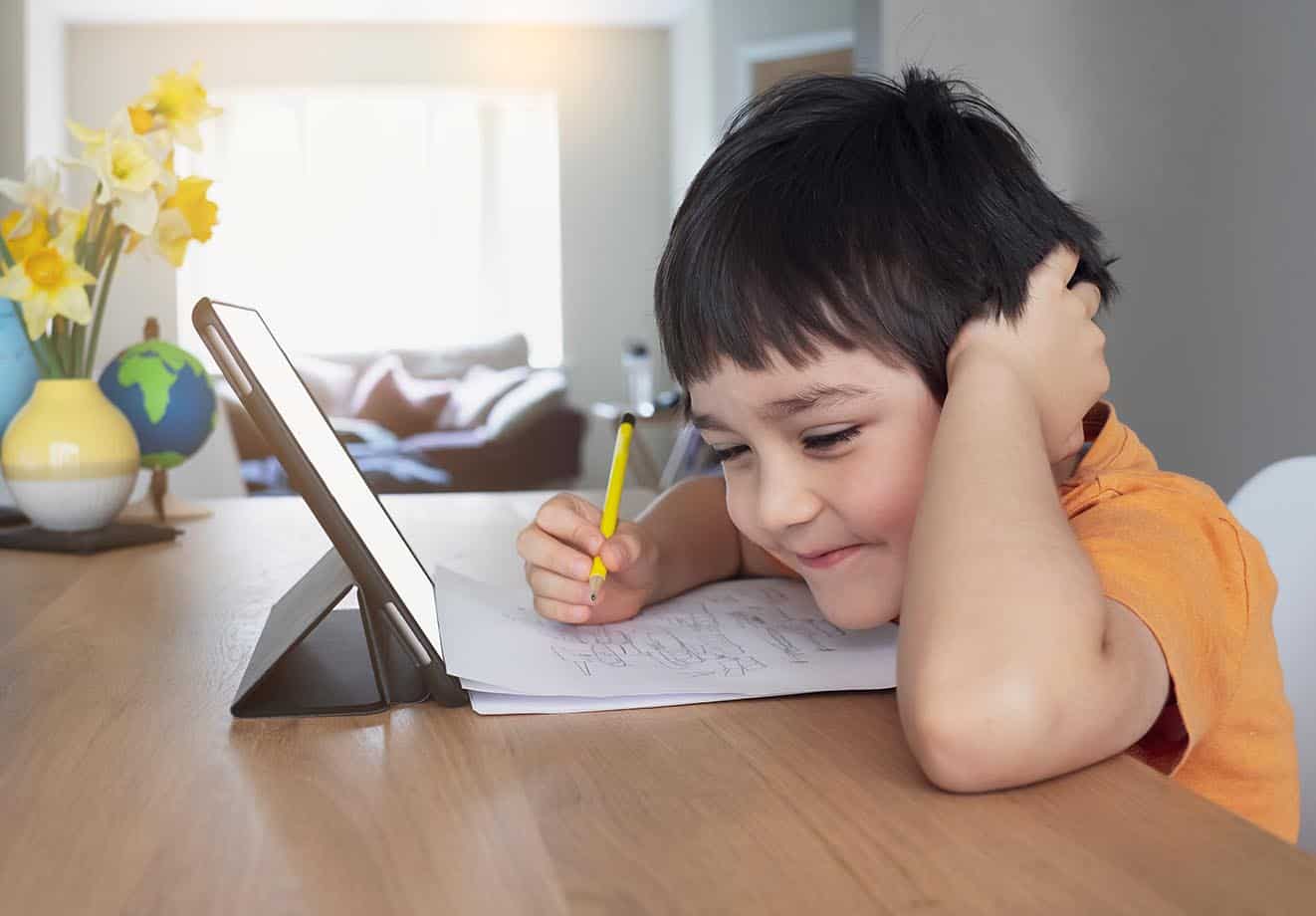 Child looking at paper and a tablet