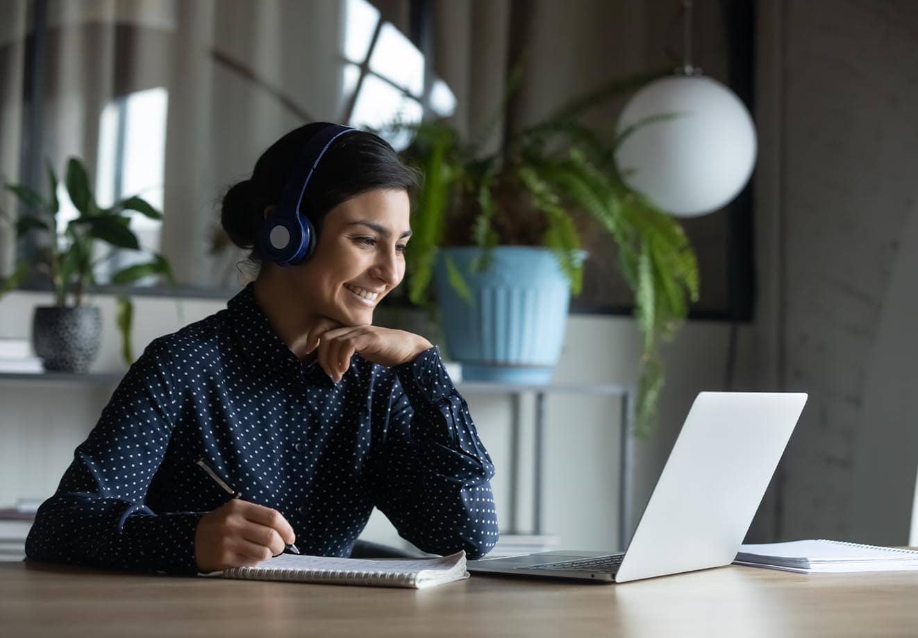 higher education college student is motivated and engaged with her online coursework as she attends class from home using her laptop