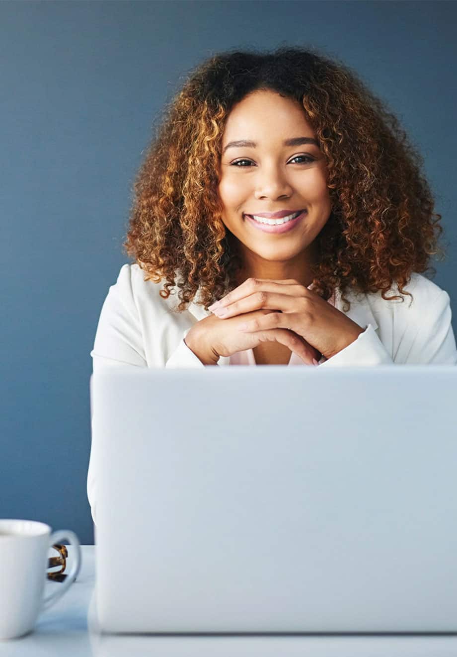 woman smiling behind laptop at desk
