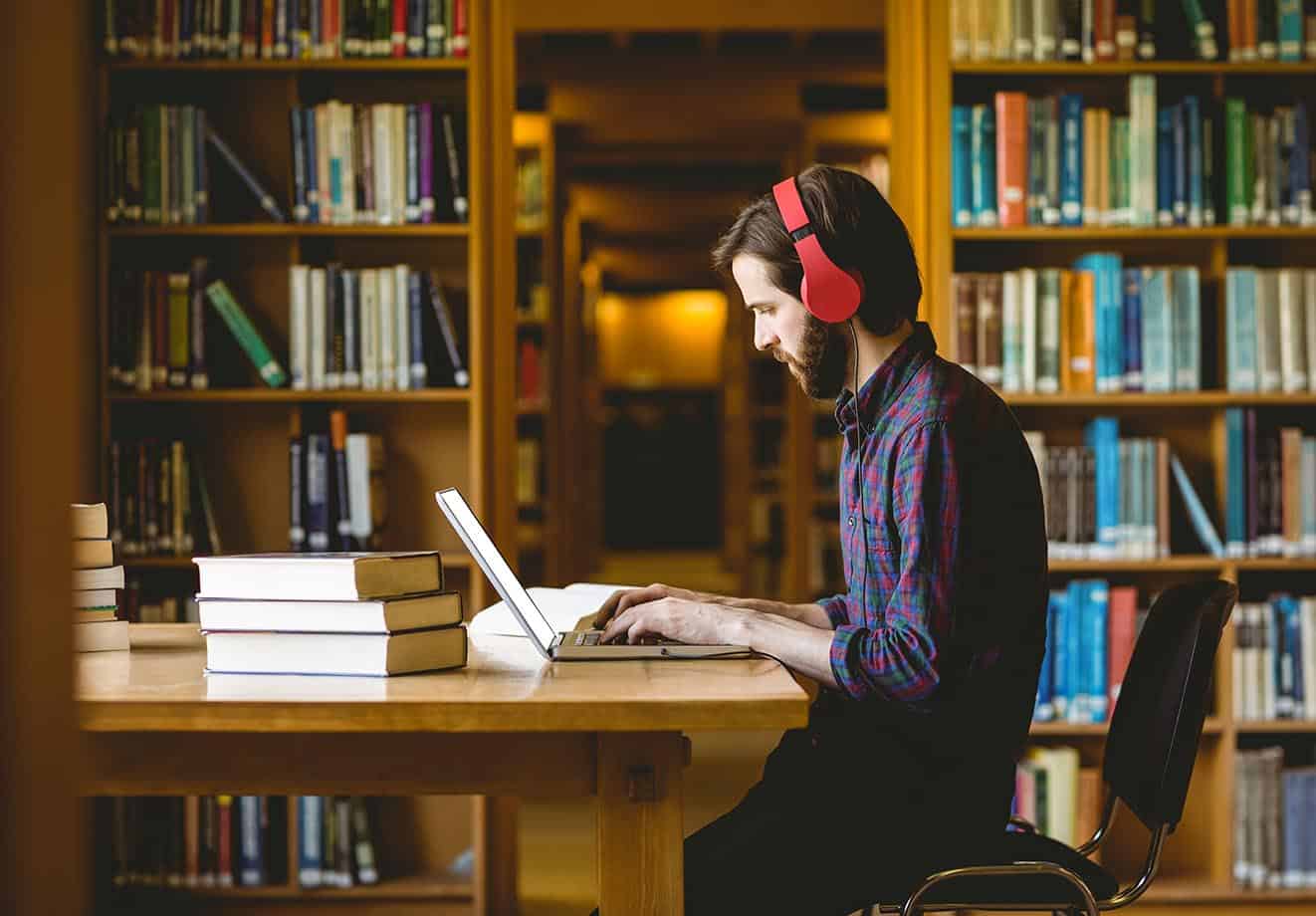 student sits in the college library, studying, using the advantages of blended learning to get the most out of higher education