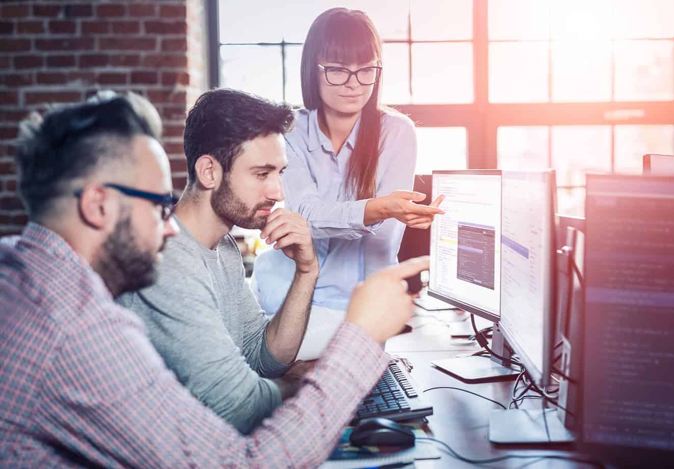 employees gather at one of their colleague's computer screens to discuss what learning and development they need