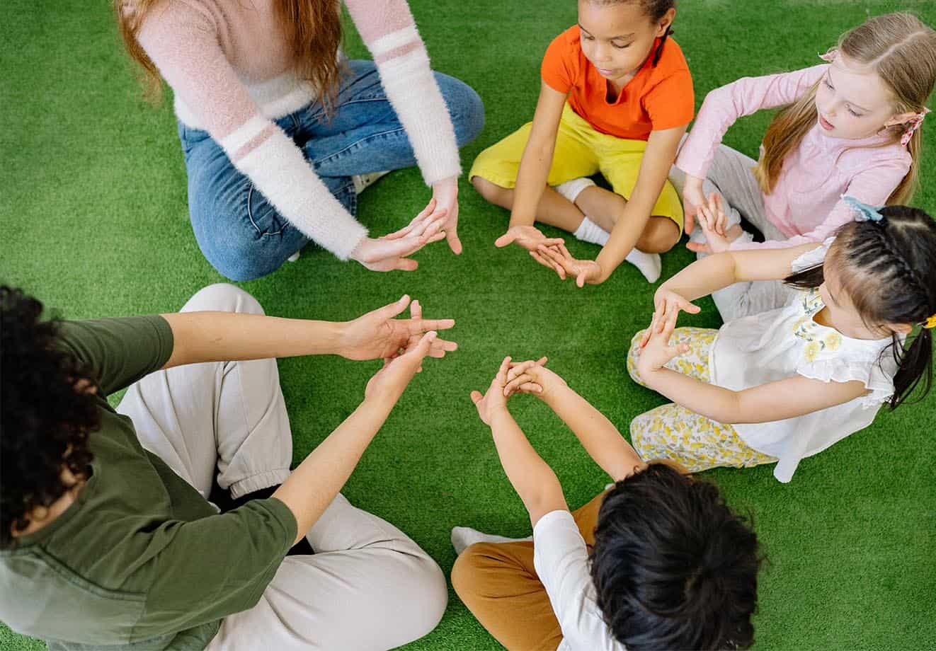Group of school children sitting in a circle on the grass