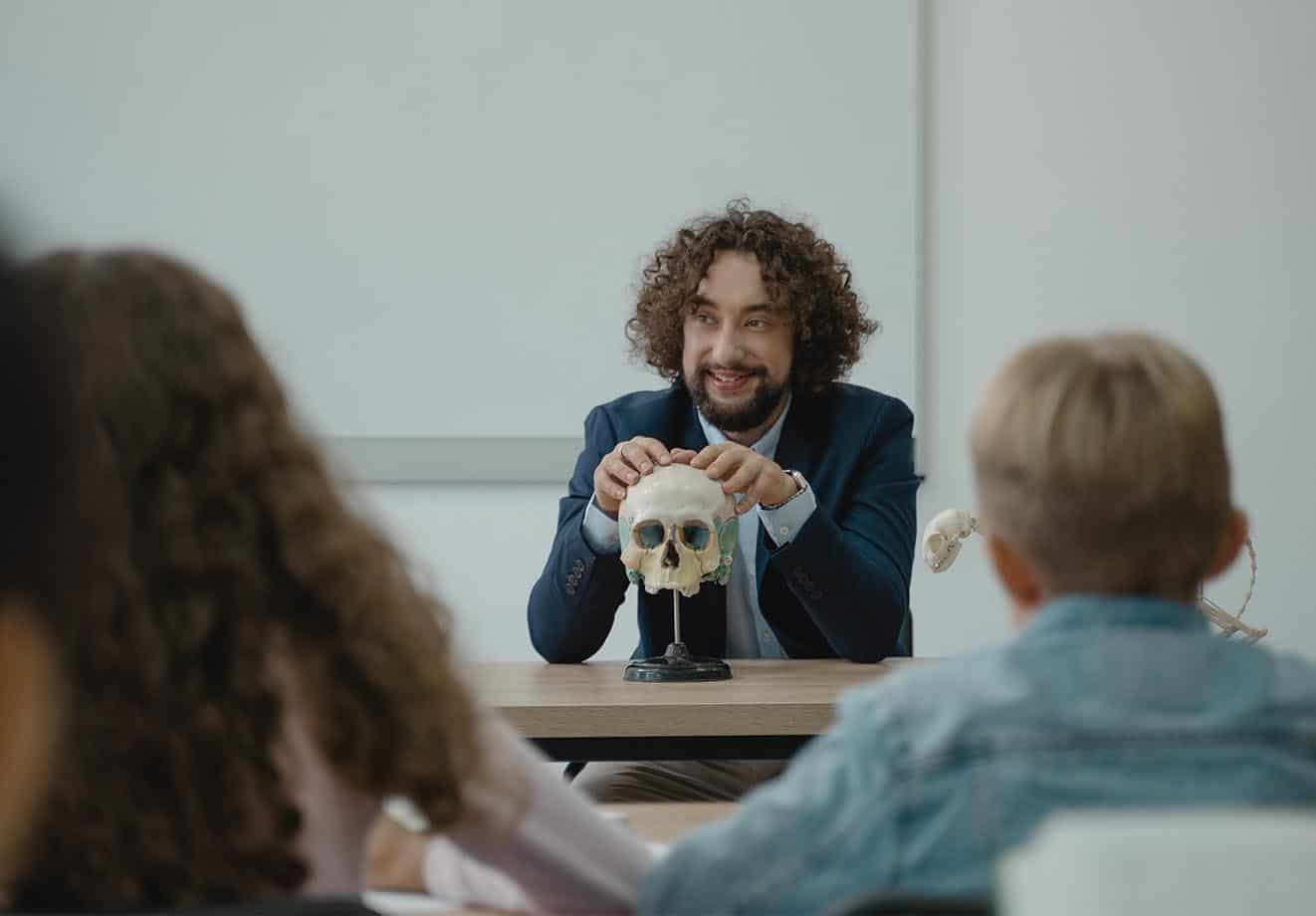 Teacher sitting at the front of the class for a biology lesson