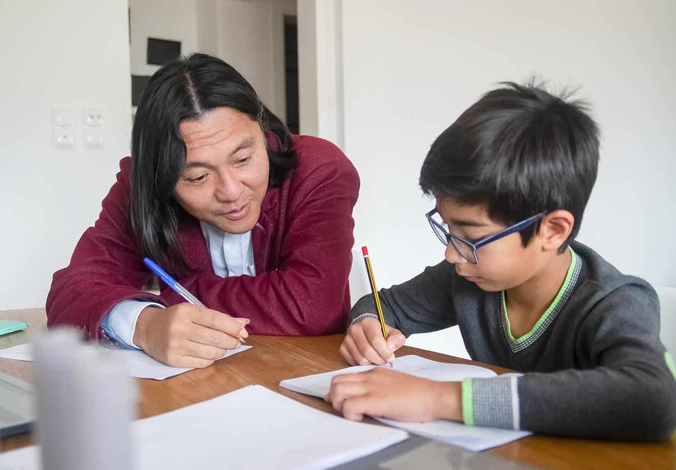 parent and child sitting at a table working on homework