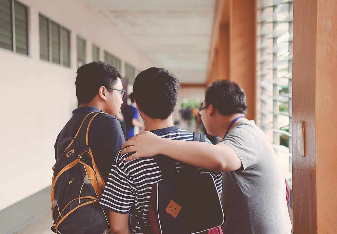 three students have fun in the school hallway as they recover from a long time away from the classroom due to covid-19