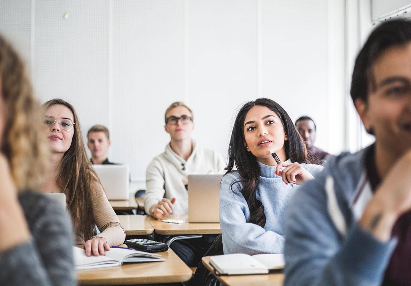 a group of college students listening in class