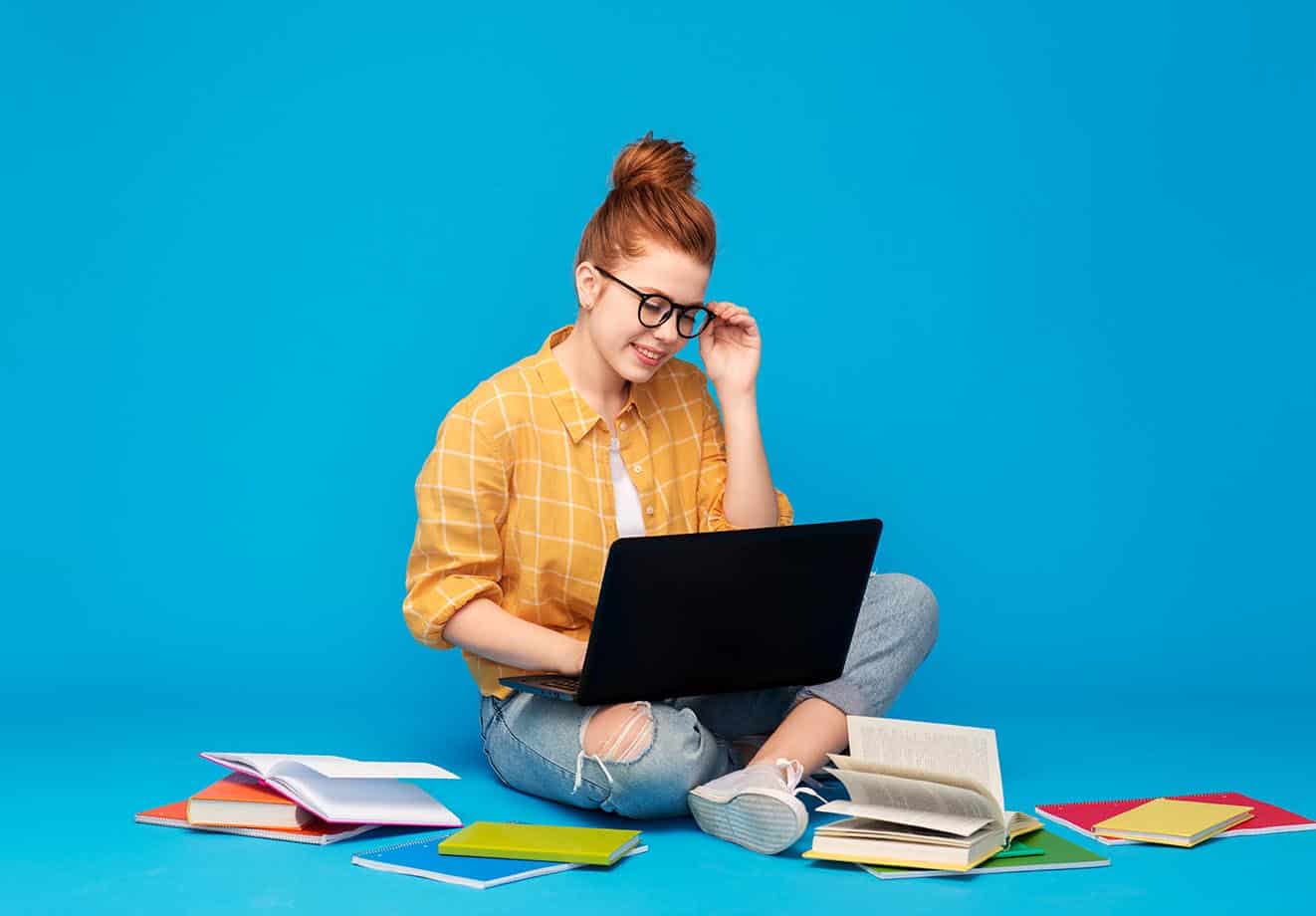 Girl-wearing-orange-shirt-with books-around-and-laptop