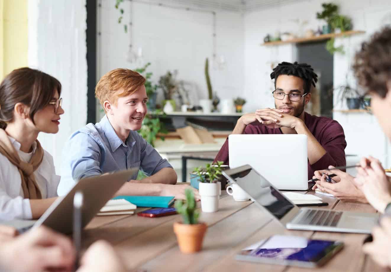 Group of people working together around a table with laptops and notebooks