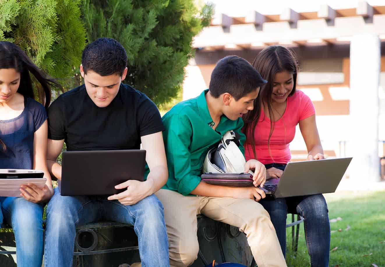 Students sitting outside looking at a laptop screen