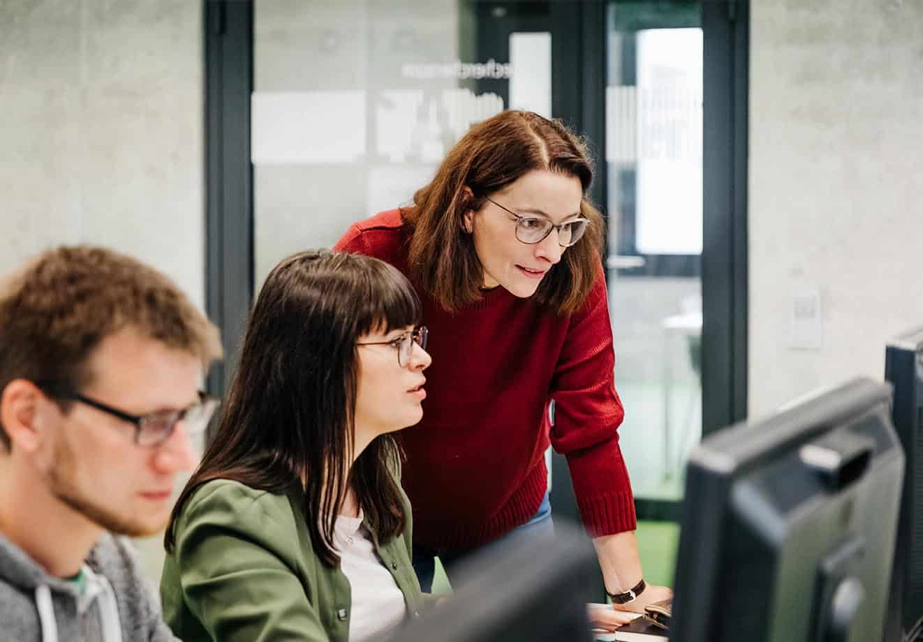 a professor guides her higher education students using computers in a blended learning classroom setting