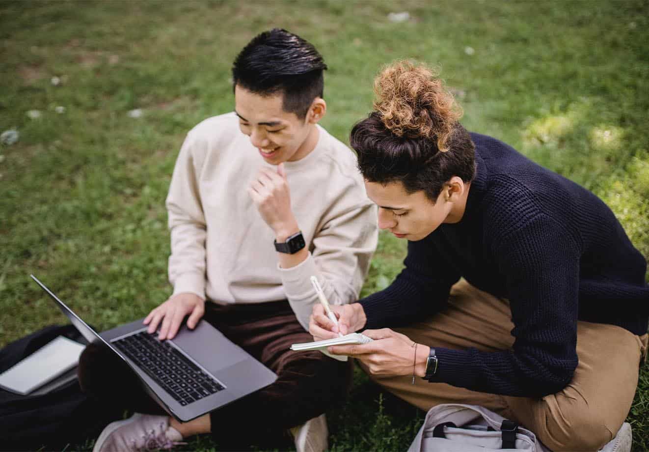 Two students sitting on the ground outsideoutside