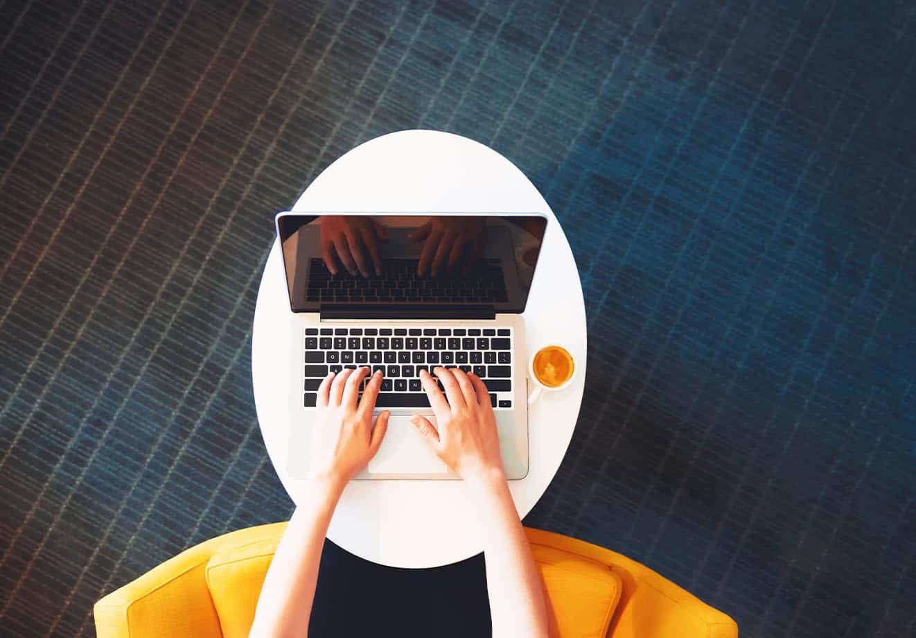 A person types on a laptop as seen from above.