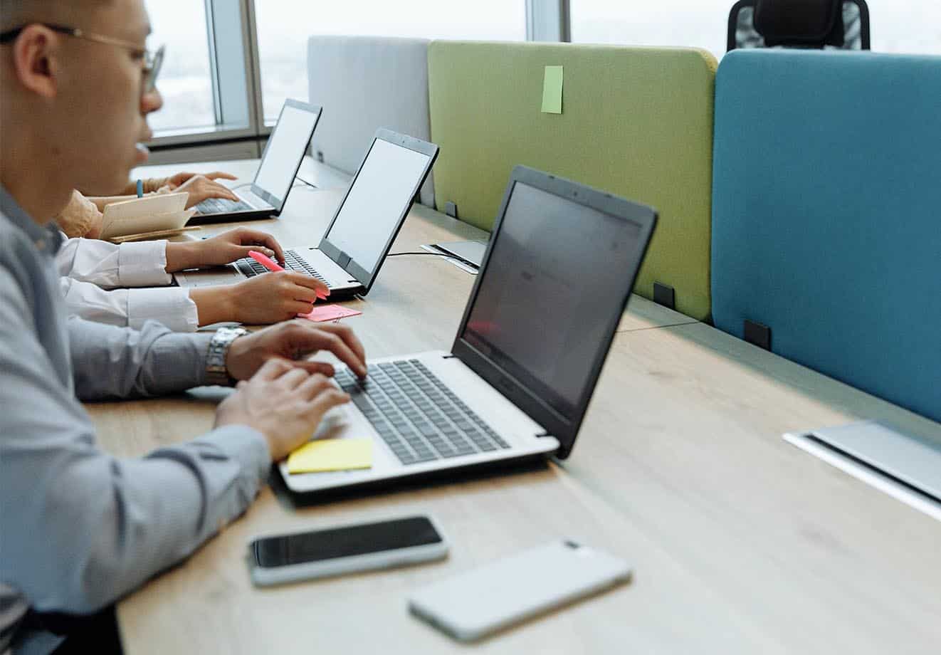 employees at work in the office using their laptops, but sometimes work at home because their company follows a hybrid work model