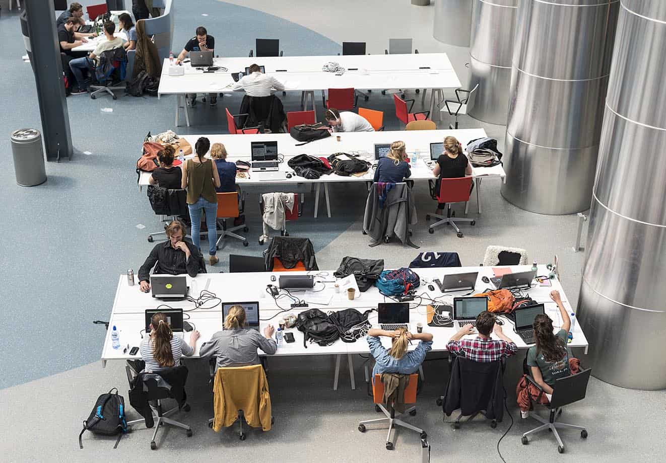 students work on campus and all have their laptops out on the desks. situations like these are why it's so important to have a secure lms to keep everyone's data secure
