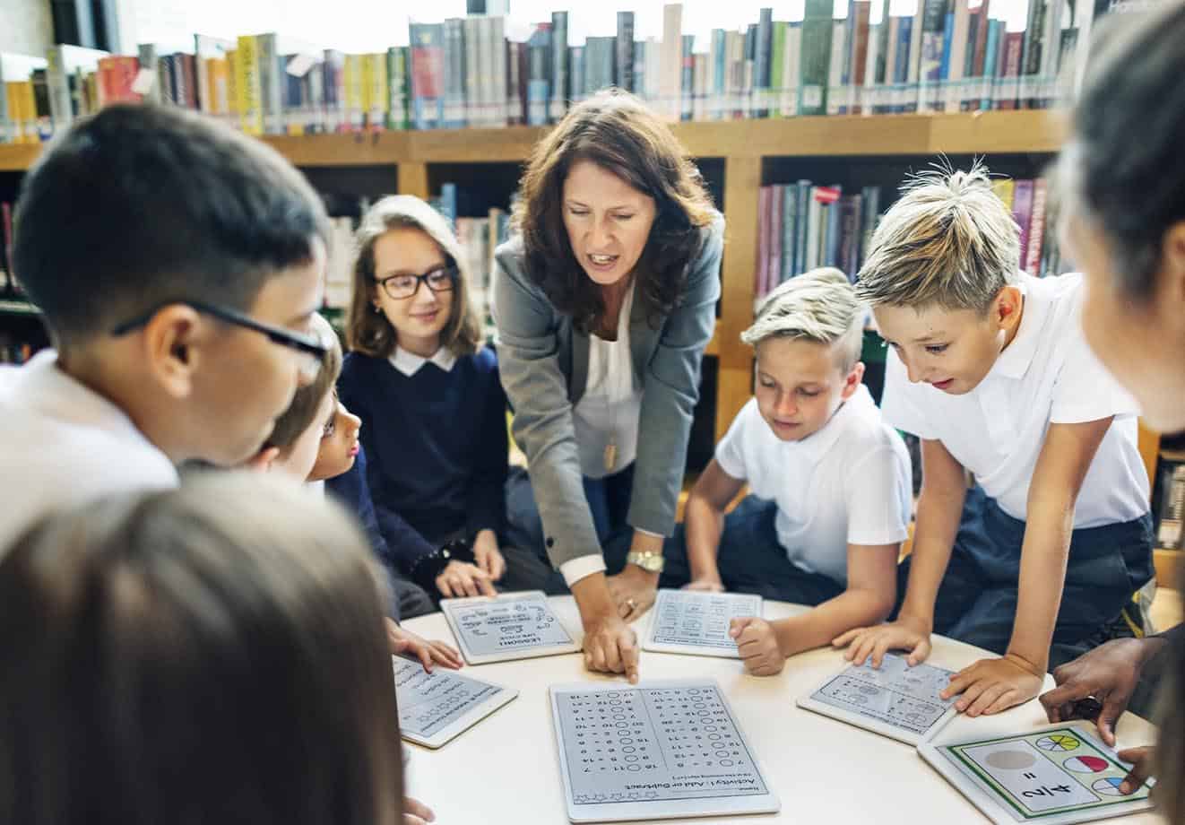 Teacher and students working together on tablets in the classroom