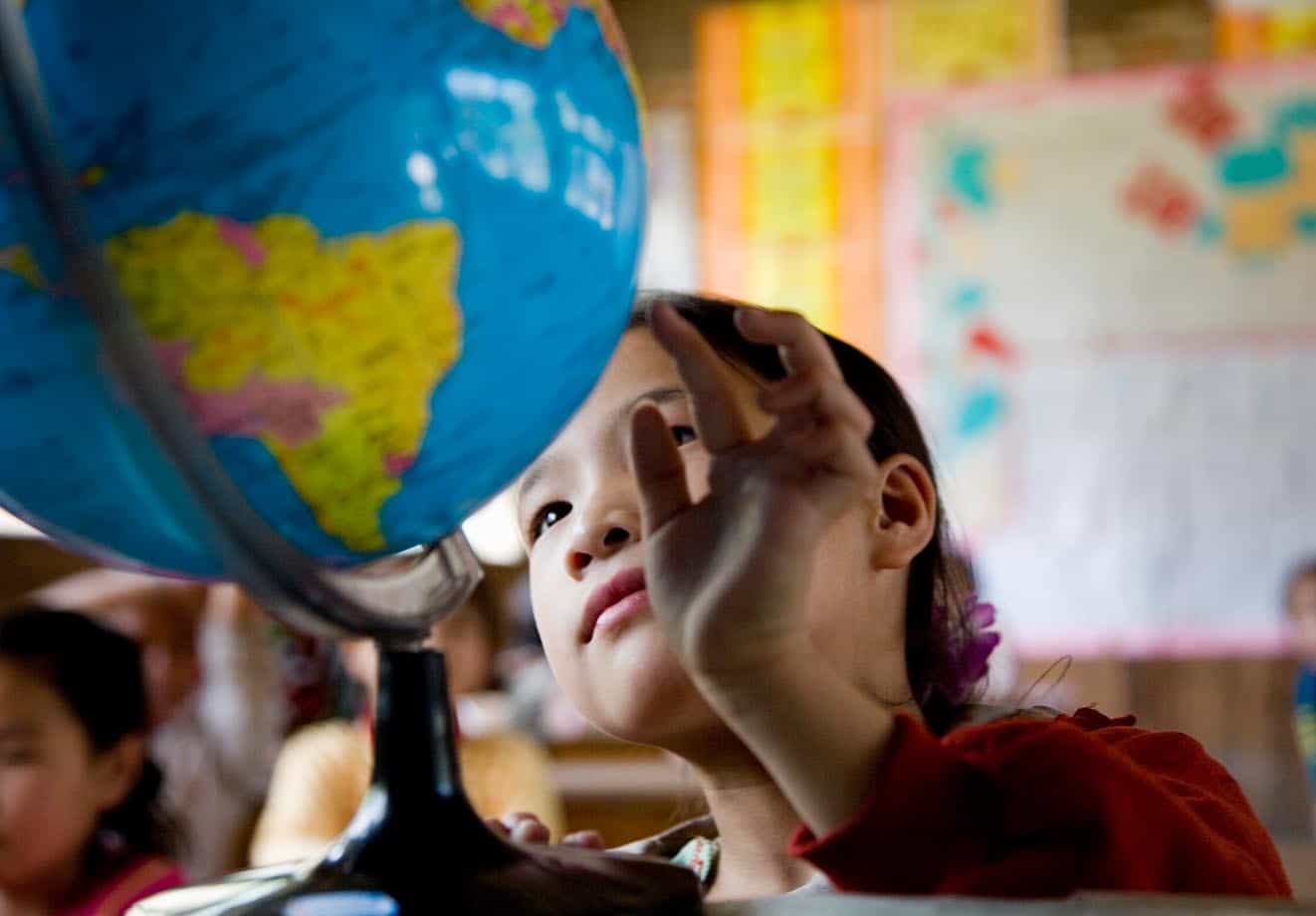 young student looks at a globe in her classroom