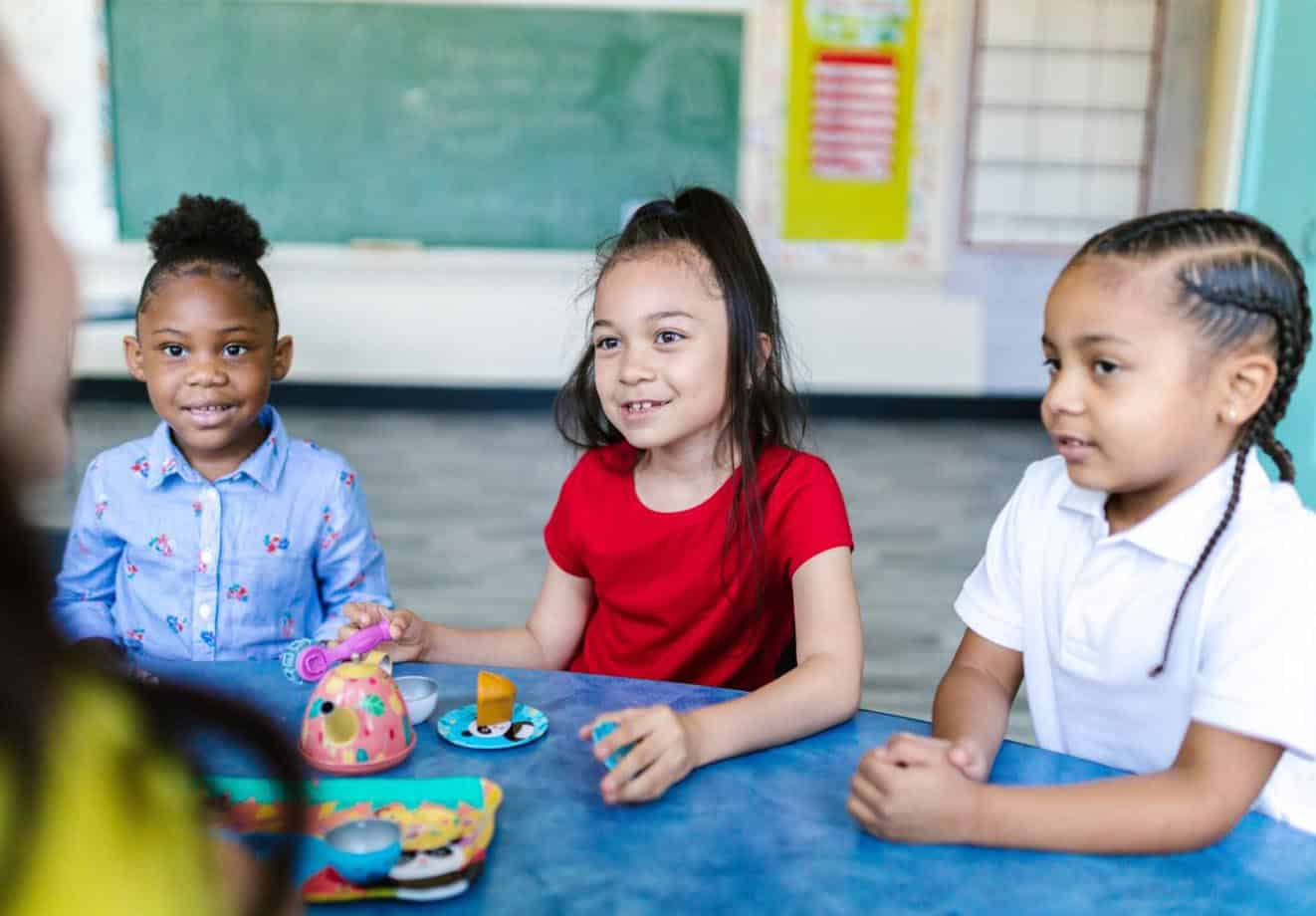 group of three school children sitting around a table