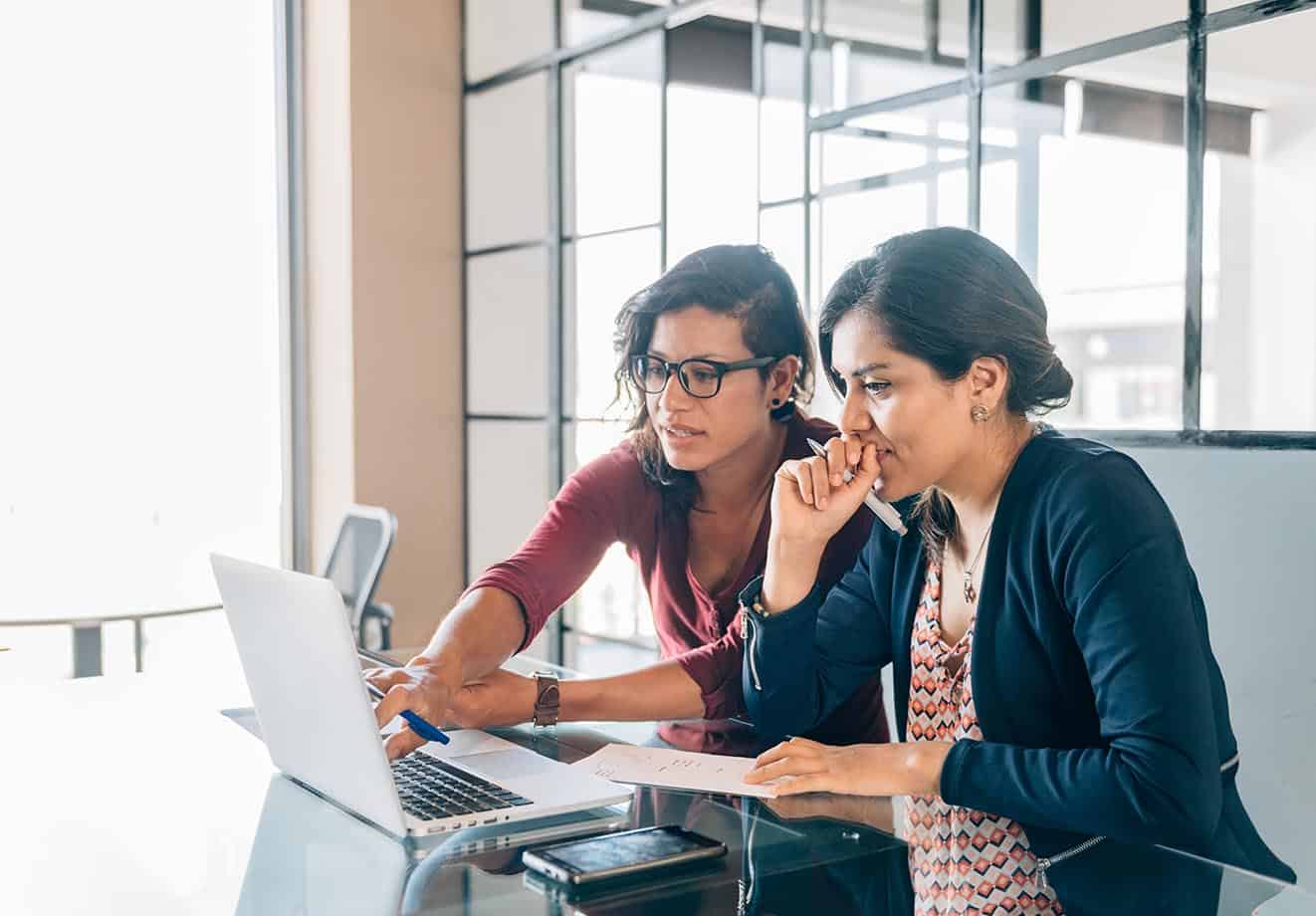 Two women in a meeting room working on a computer