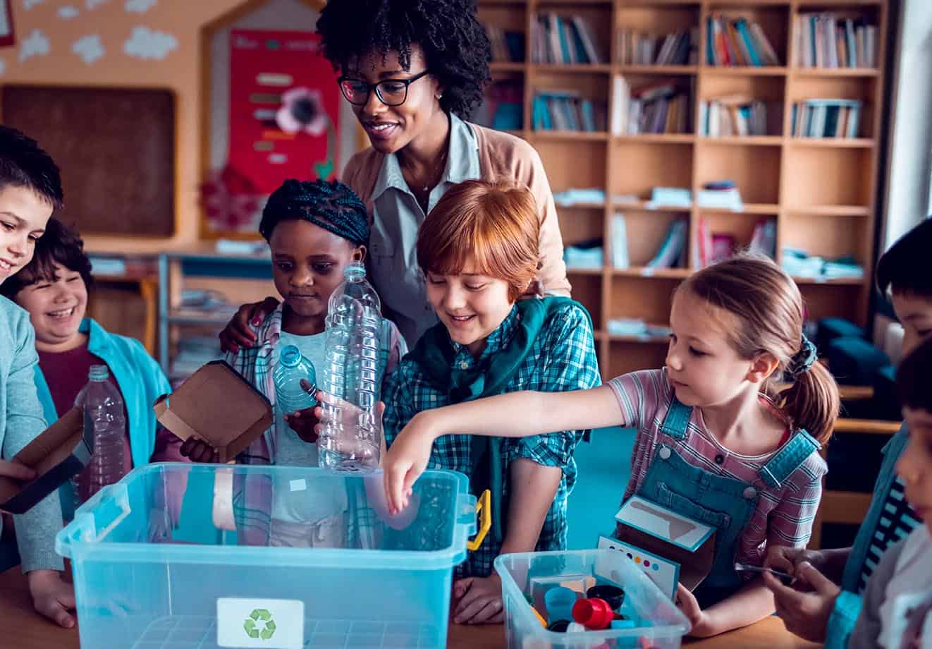 teacher standing behind students working on a science project