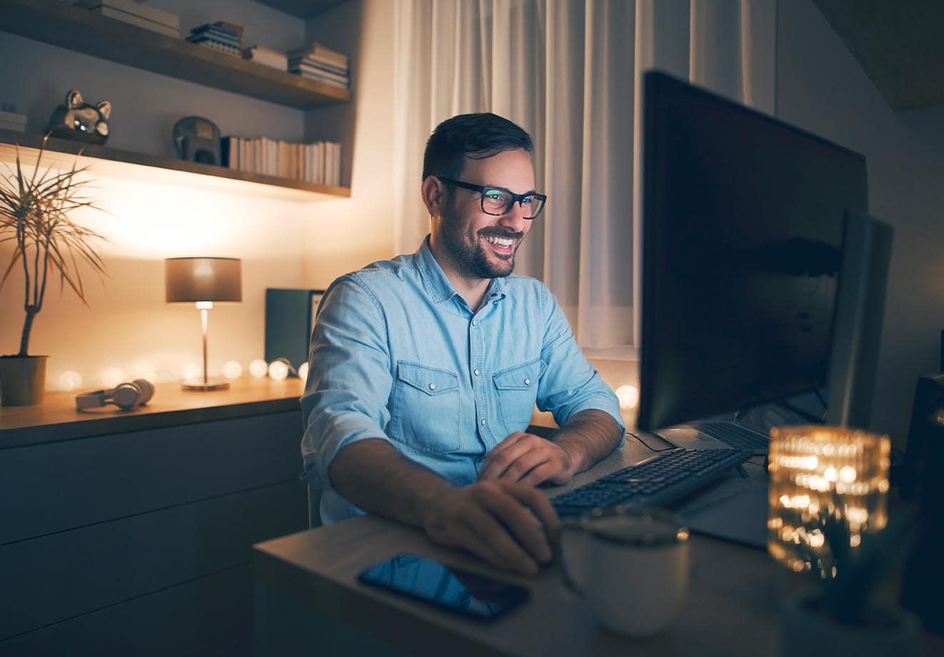 Man smiling and looking at a computer monitor