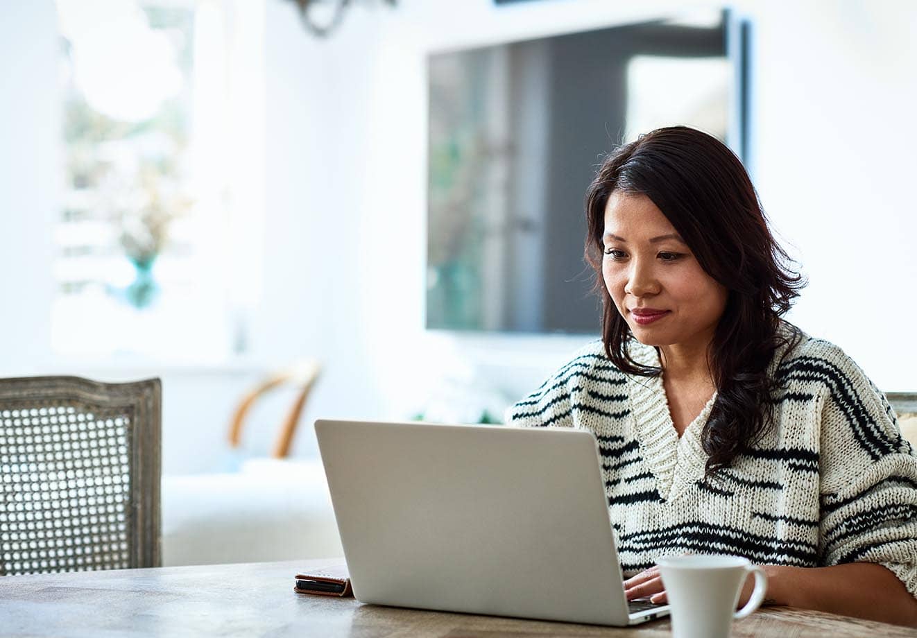 woman sitting in front of a laptop with a contemplative look on her face