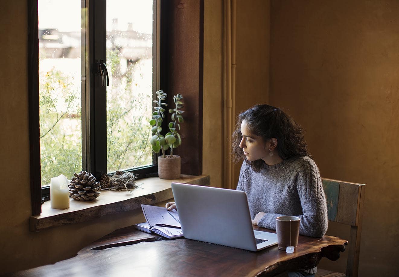 A woman in a coffee shop designing learning content on a laptop