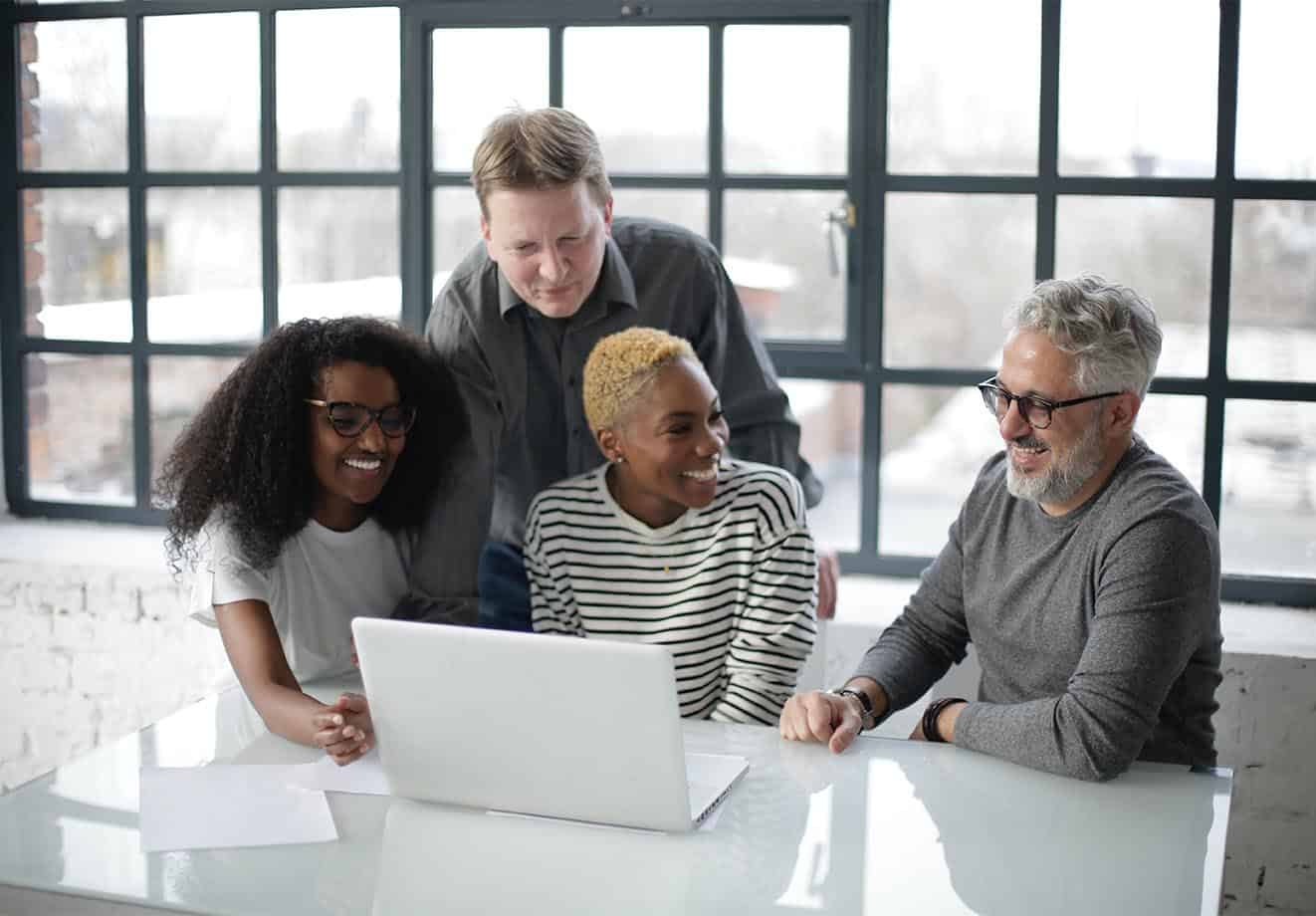 Four people working together around a laptop