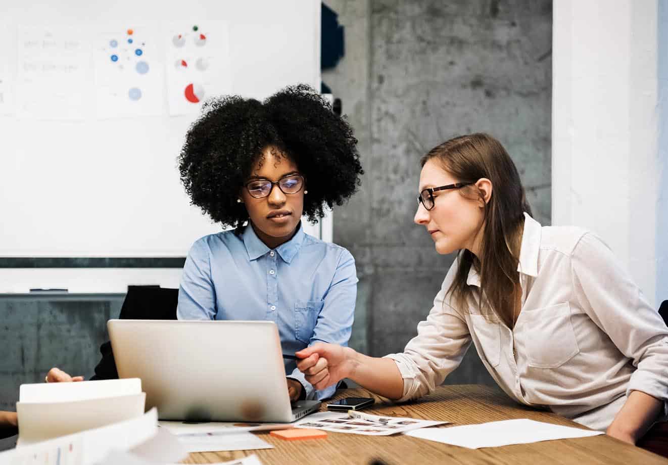 Two women working on data analysis in a meeting room