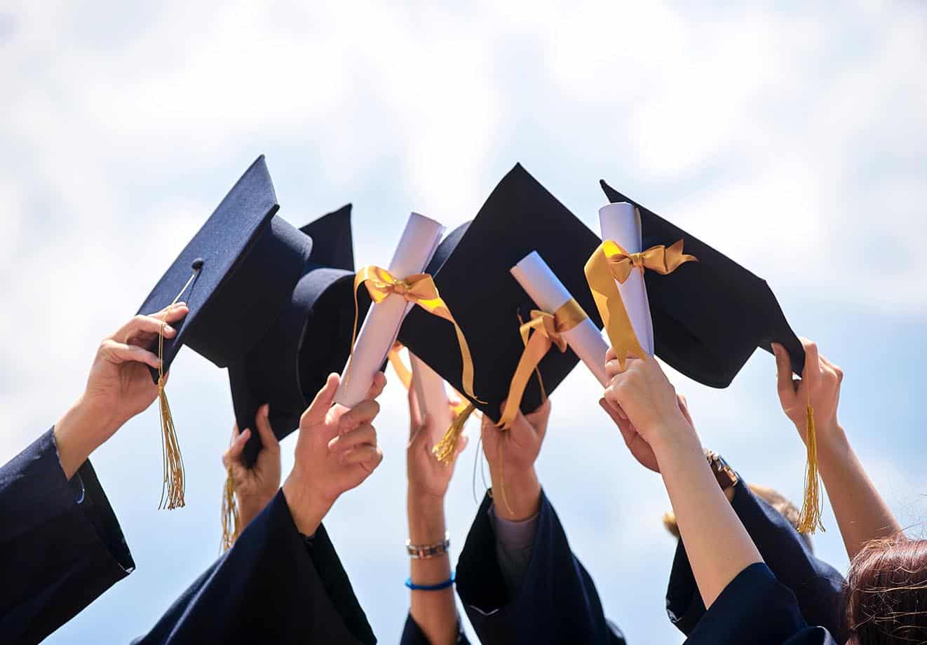 group of hands holding up graduation caps