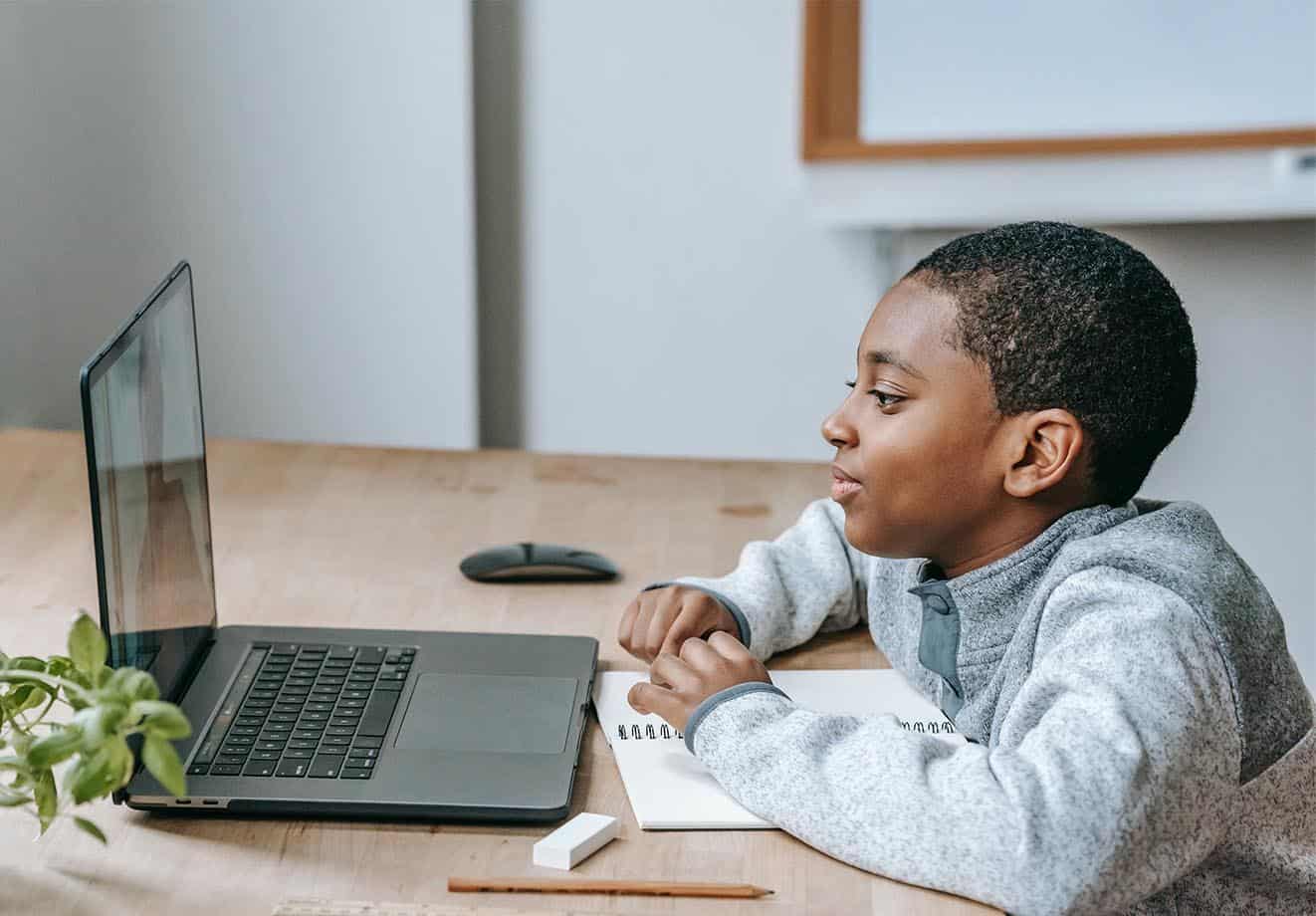 A young student uses a laptop at a desk.