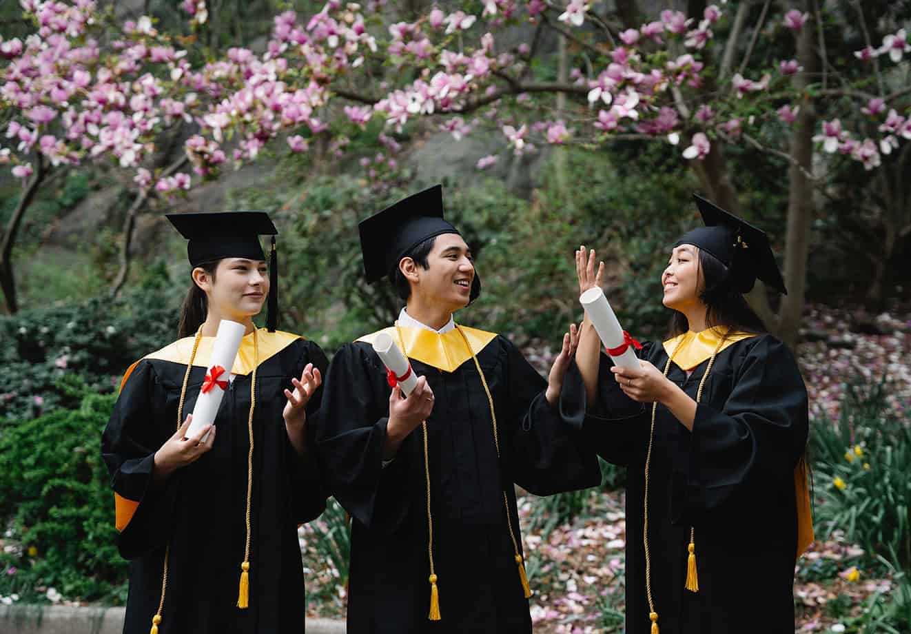 three students in graduation cap and gown