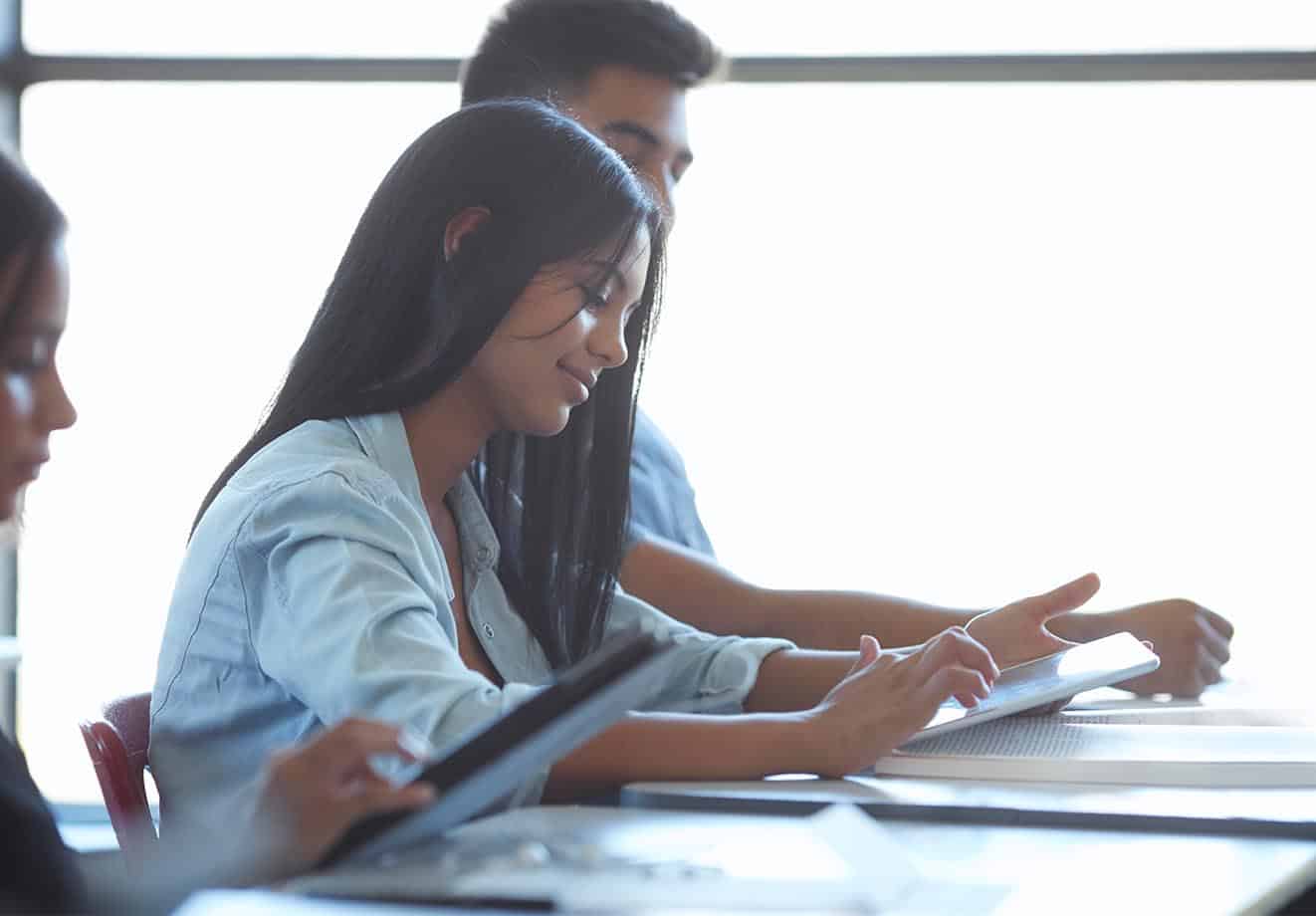 Student sitting at a desk and holding a tablet in her hands