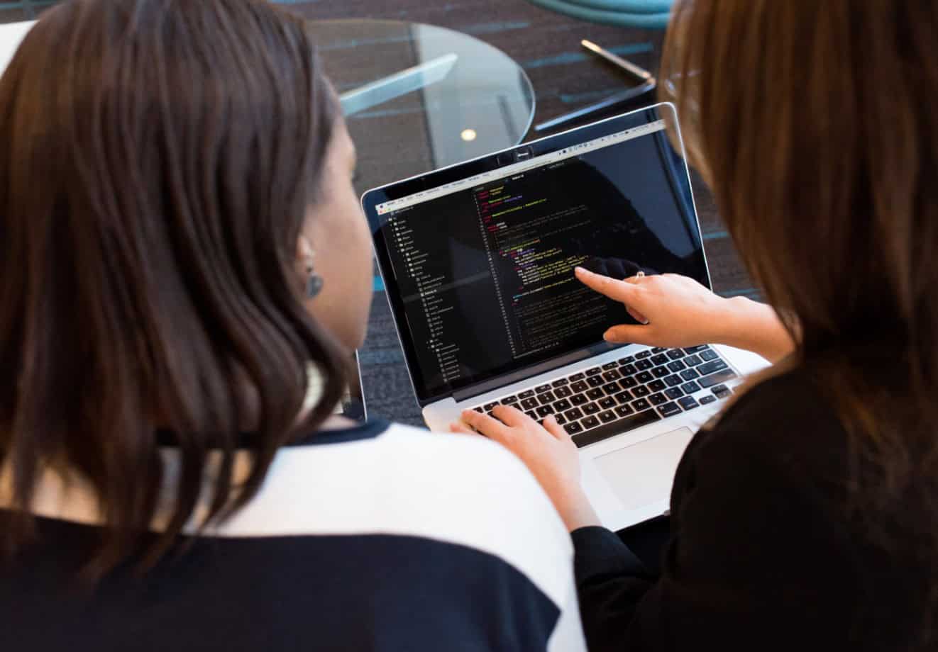 Two people working on code on a laptop.