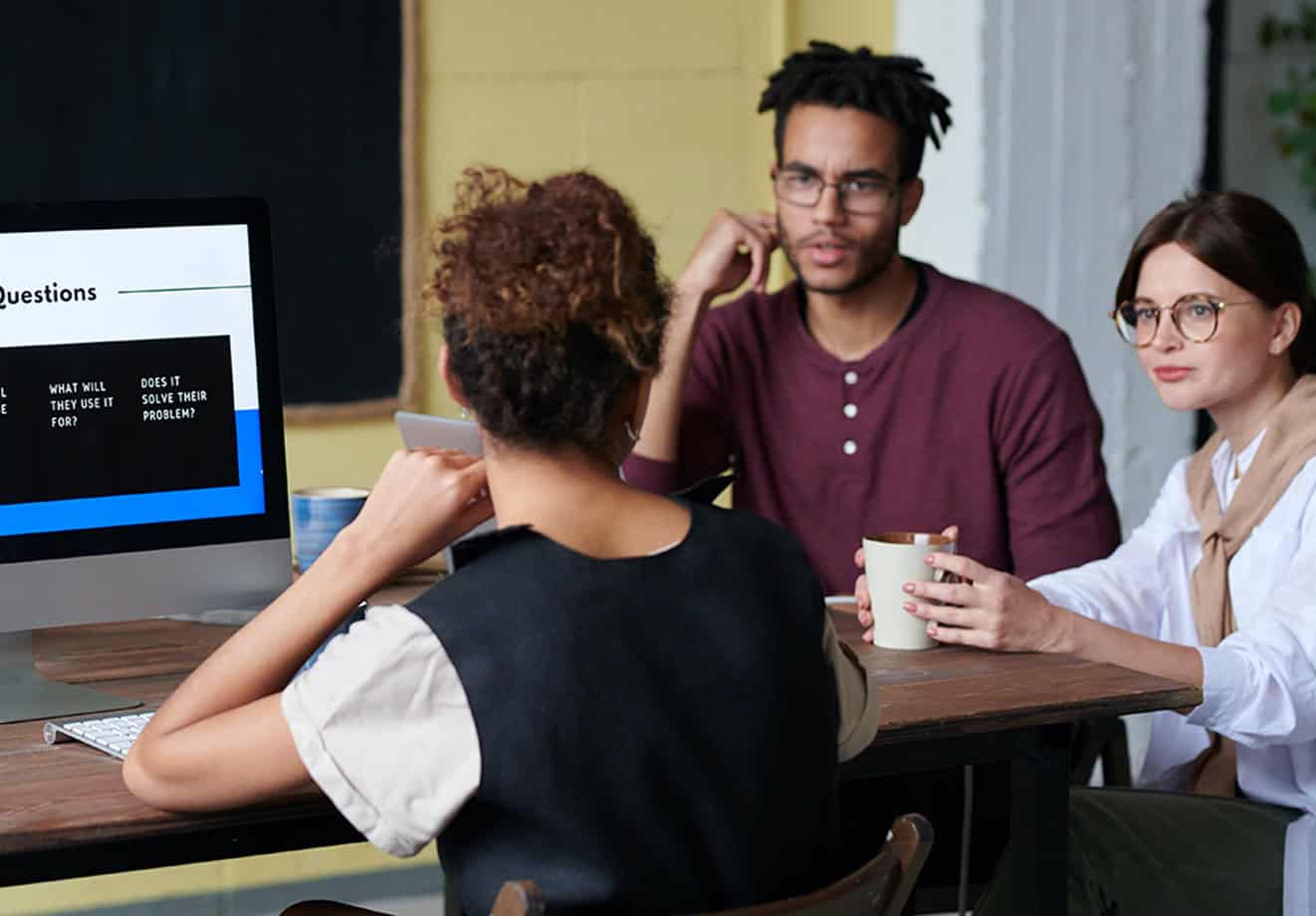three people sitting at table talking