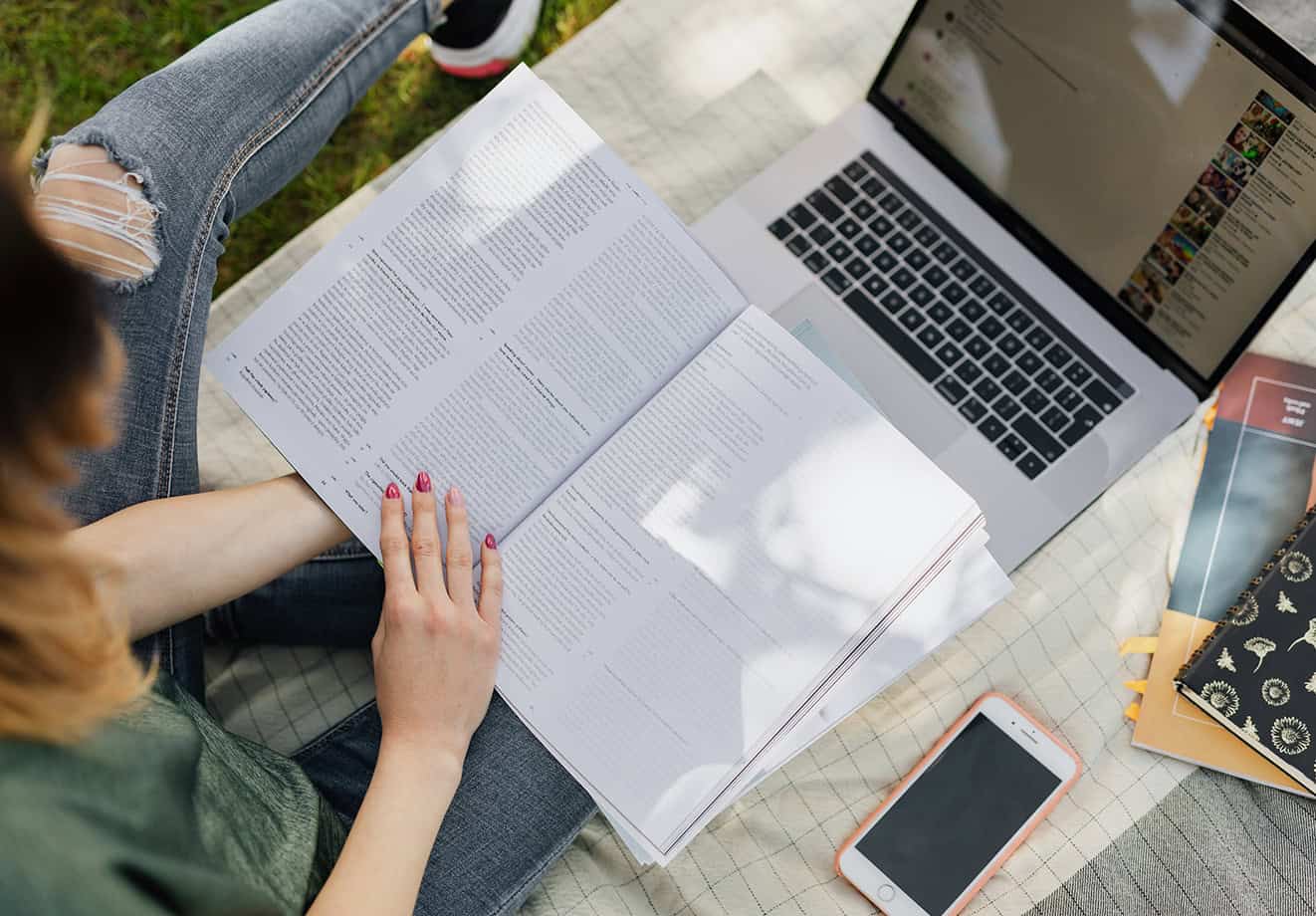 overhead shot of person with book open over laptop