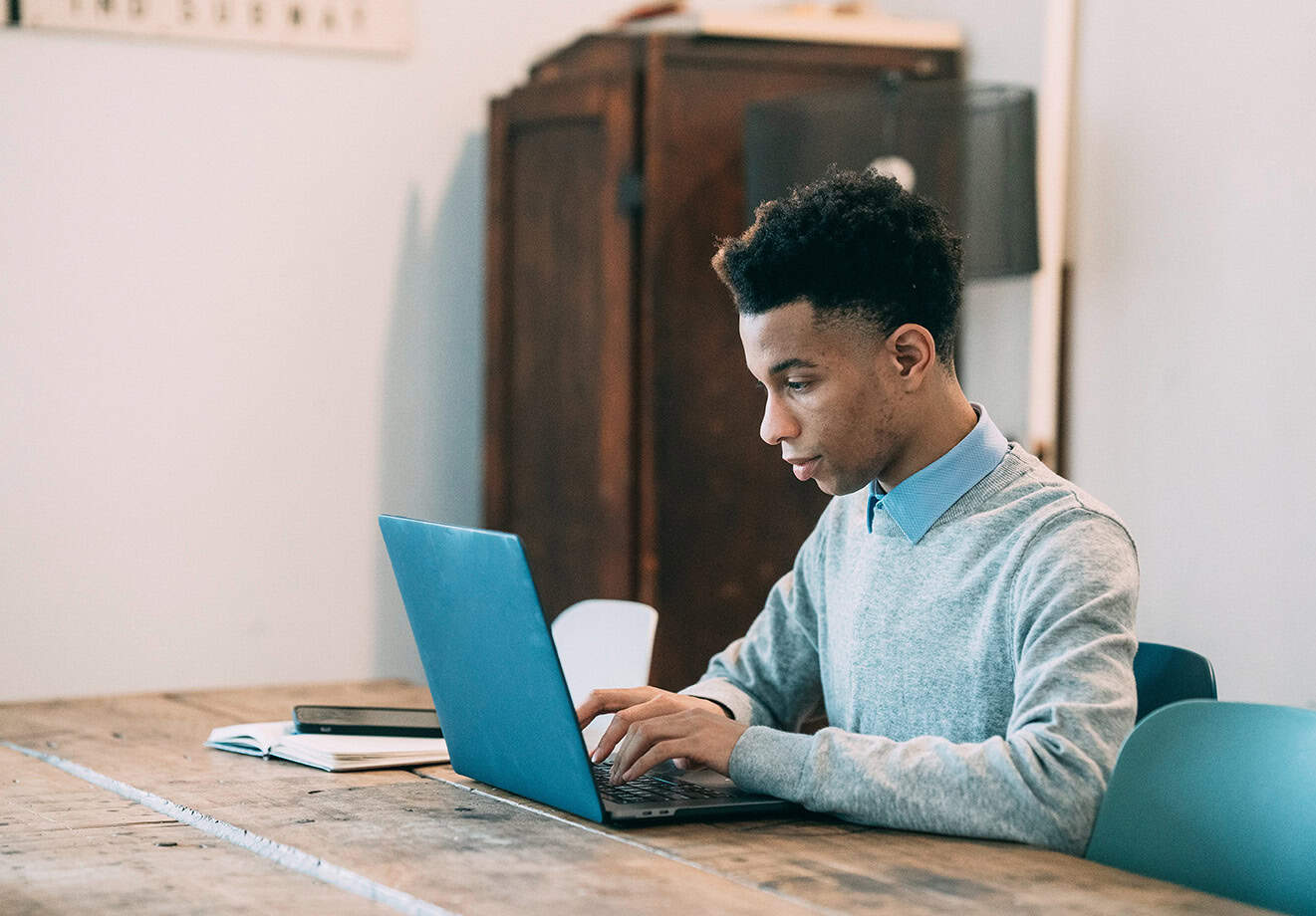 man sitting at table using laptop