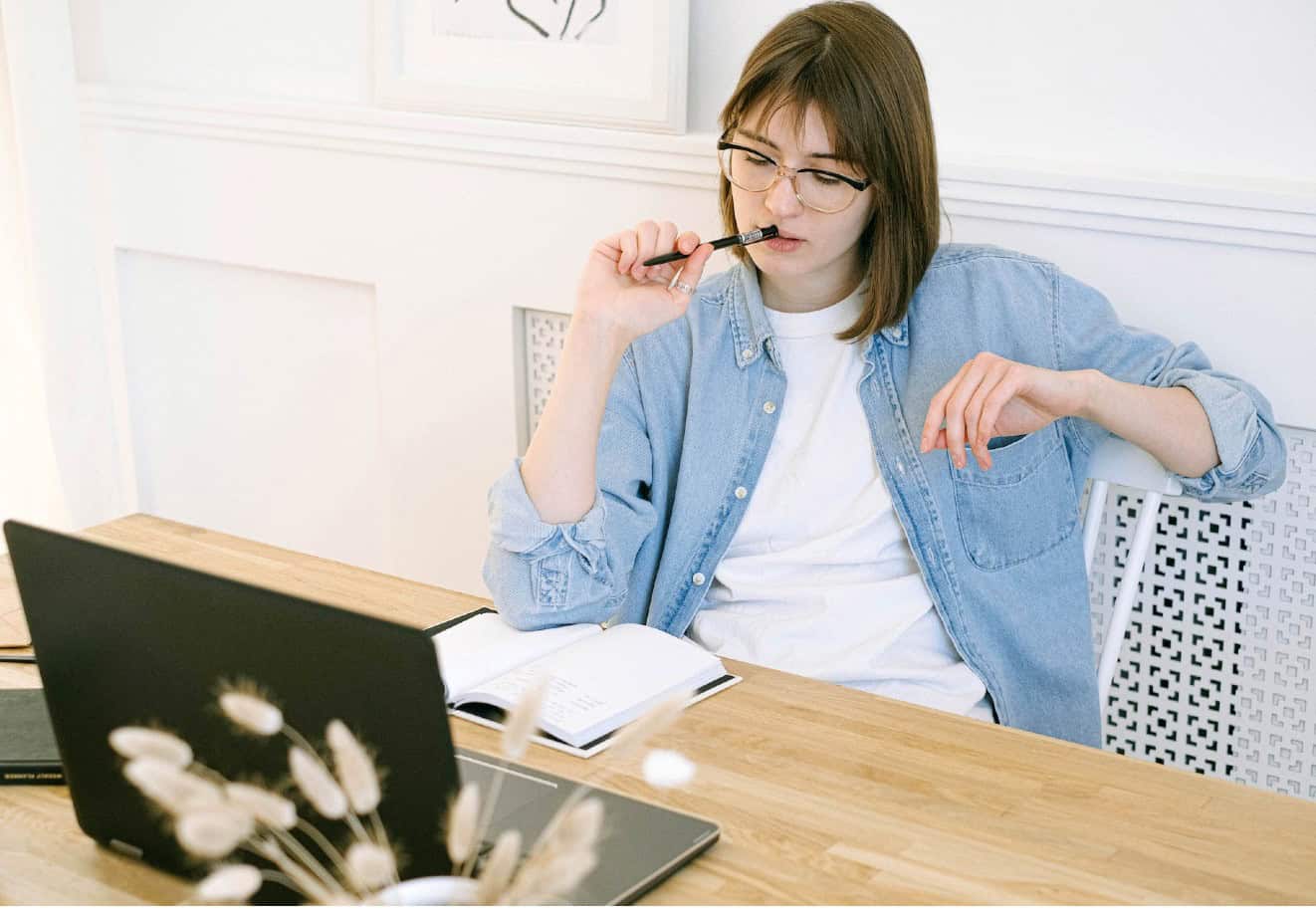 woman thinking in front of laptop and pad of paper