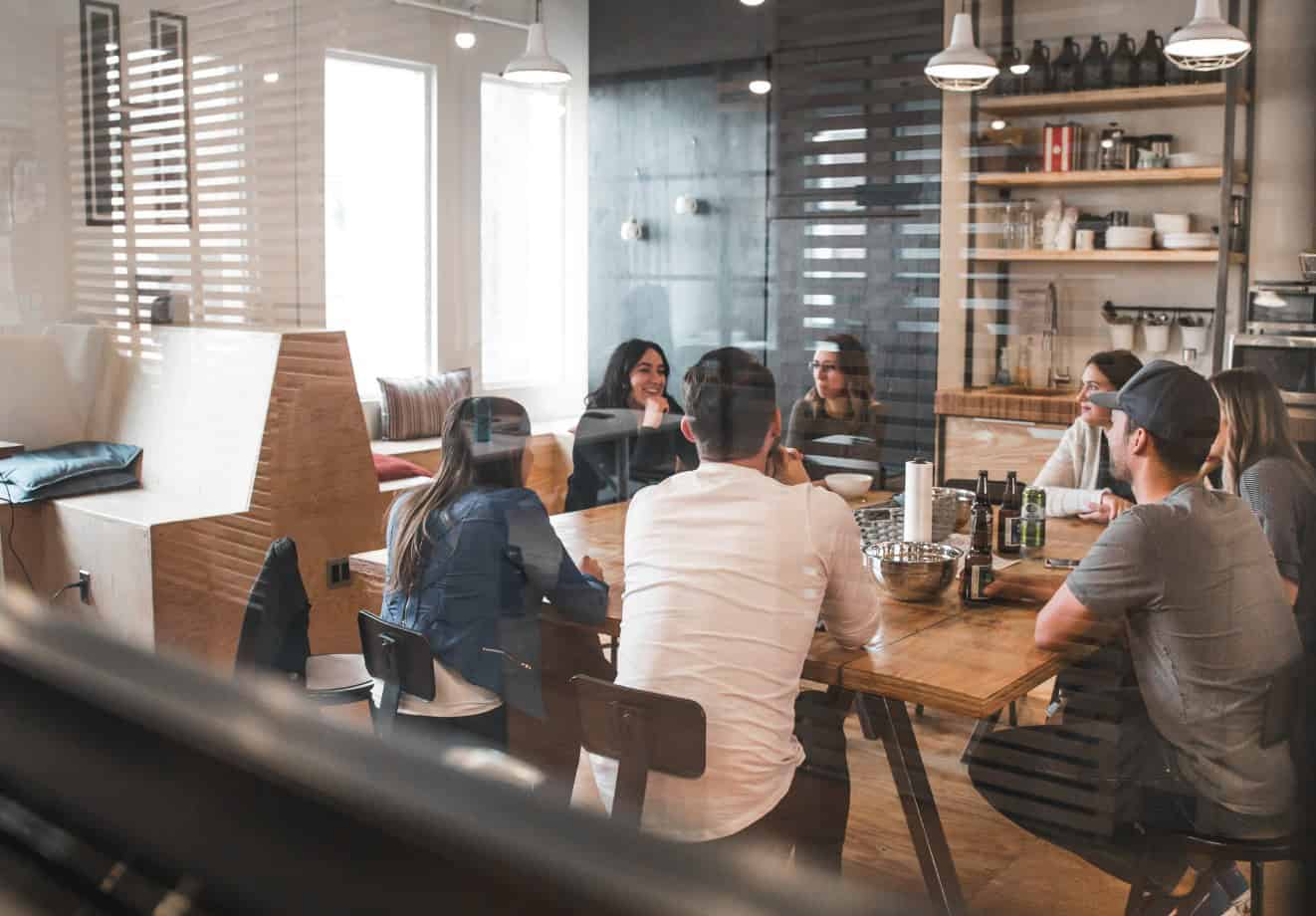 A group of co-workers sitting around a large table and talking