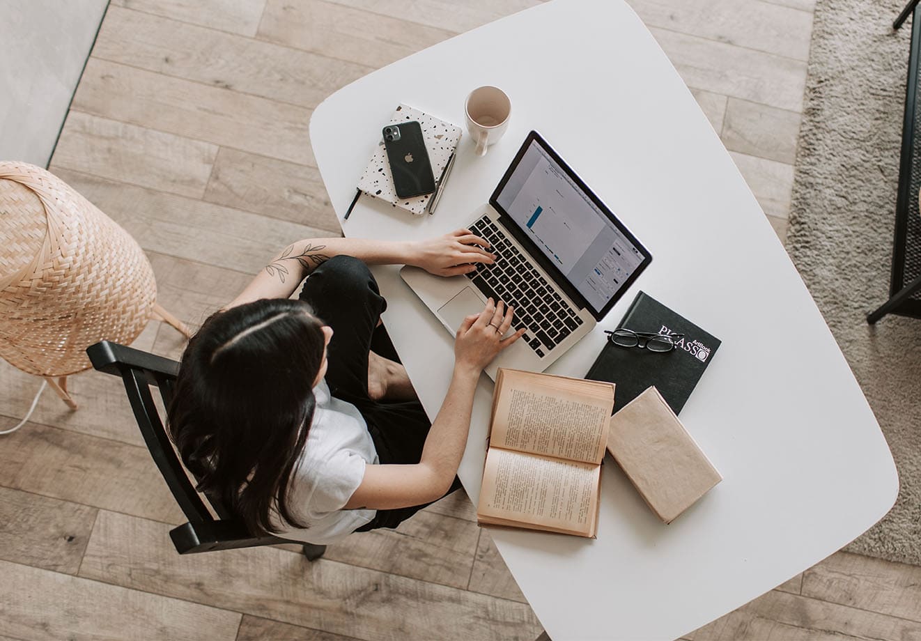 A woman types on a laptop in a bright room.