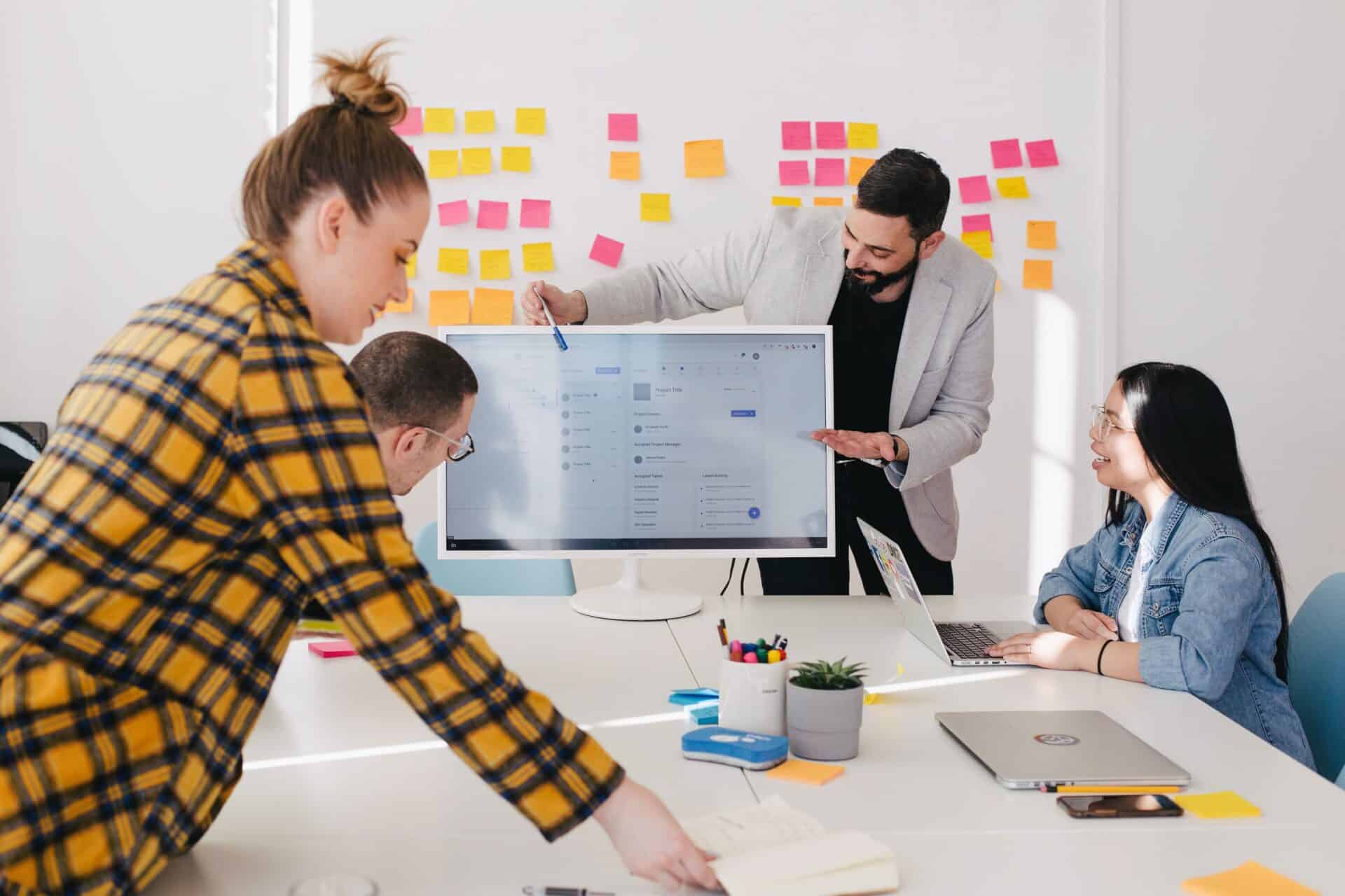 Four people sit around a desk and discuss corporate change management