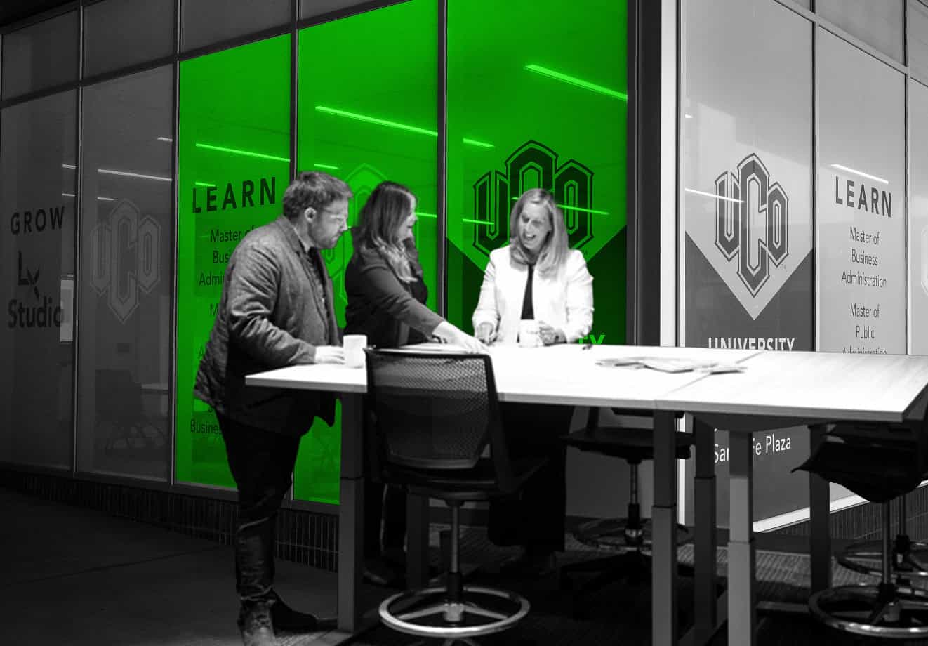 Three staff members at UCO study a document at a table.